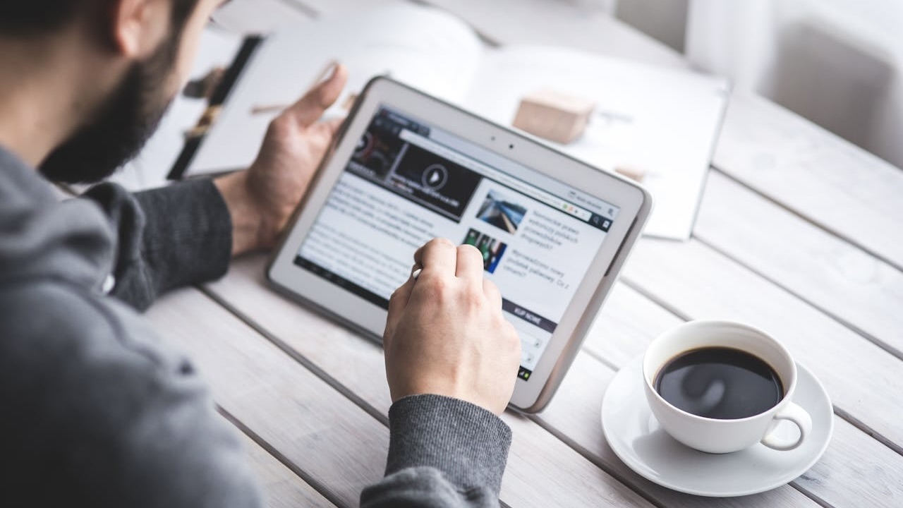 Businessman having a coffee break while reading the business news on his ipad