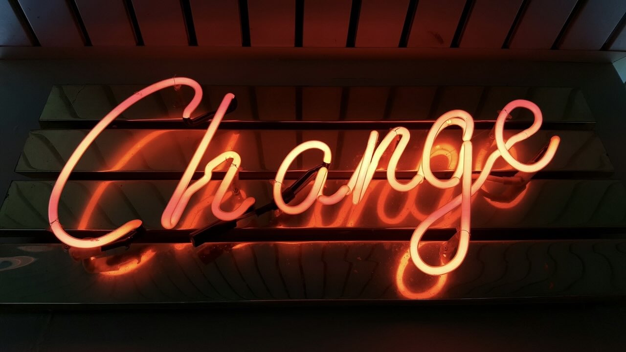 Neon orange sign on a wall with the word Change on it