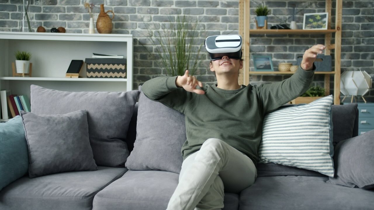Young man sitting on his couch while wearing VR headset