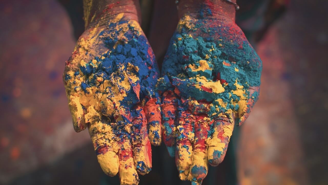 Two hands covered in various chalk colours