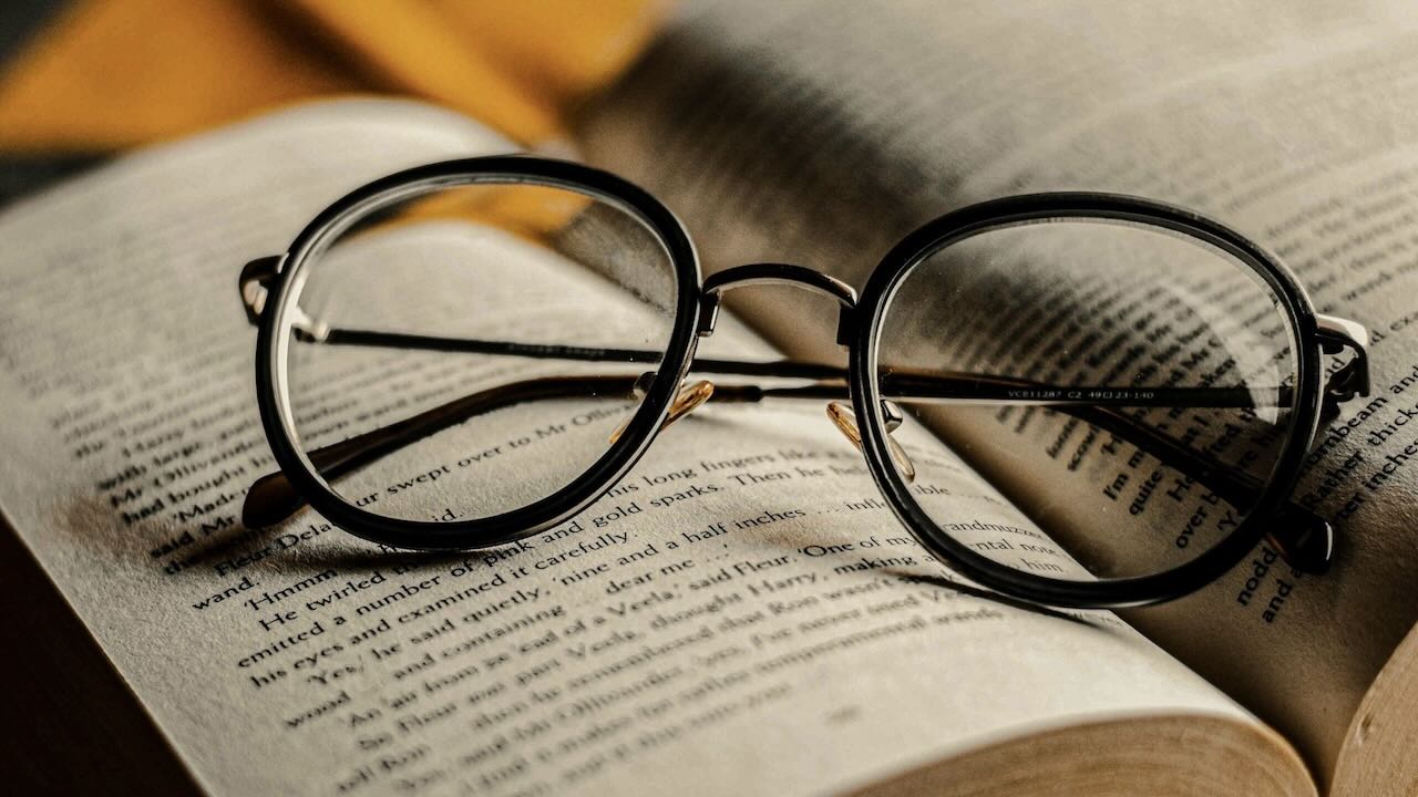 Book with a pair of reading glasses resting on a page