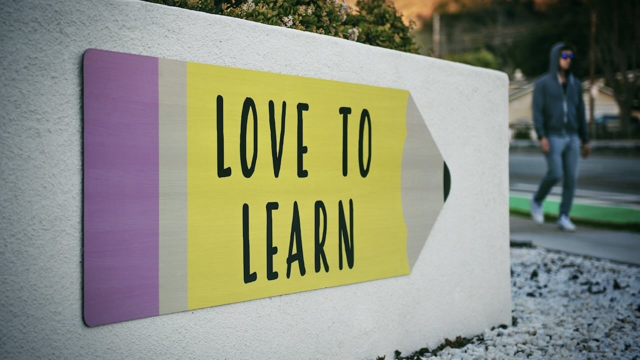 Man walking past a sign saying love to learn