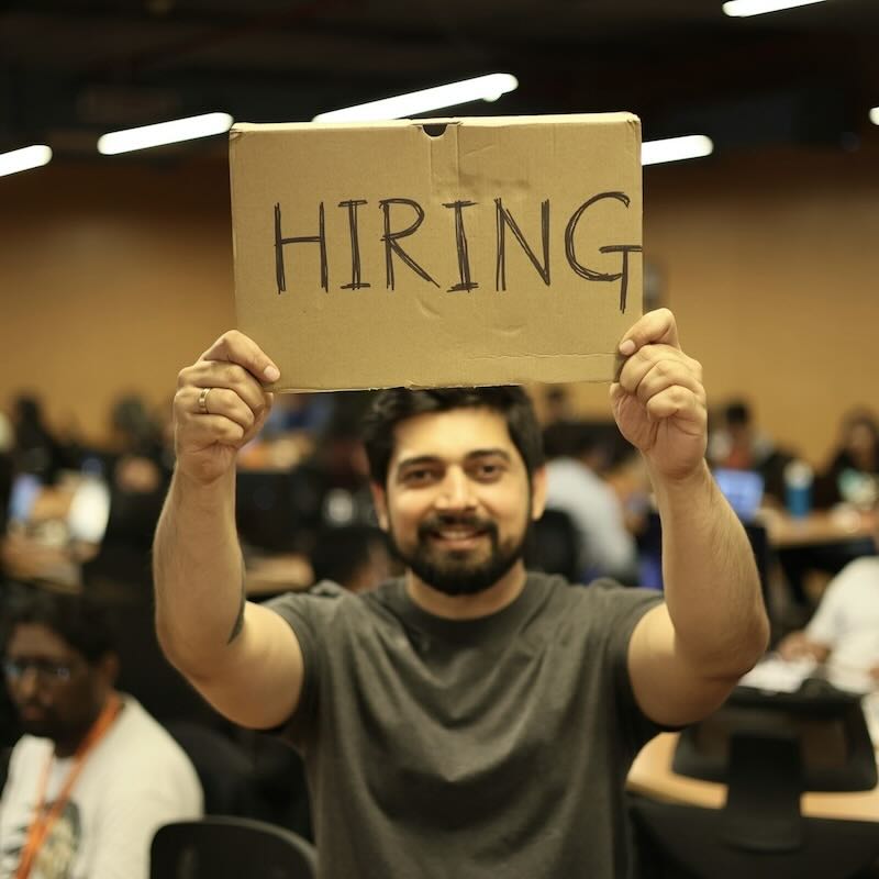 HR leader standing up at an event while holding a board that says hiring